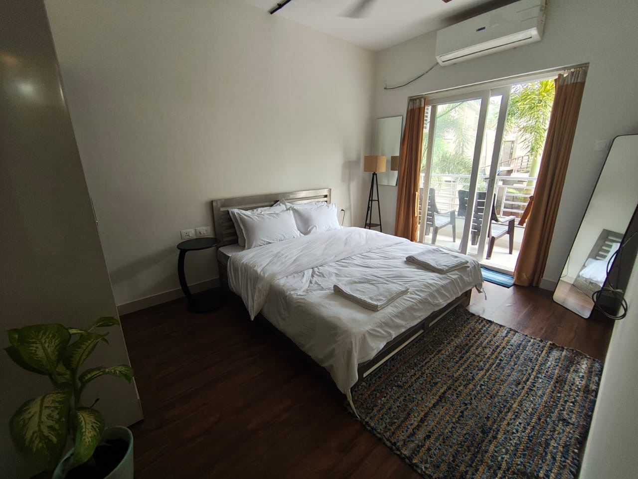 Bedroom in daylight with sliding balcony doors, woven rug, and side table