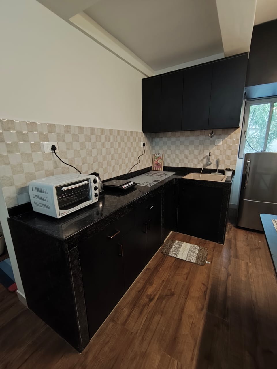 Compact L-shaped kitchen with microwave, induction, and stainless fridge